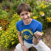 Eric Middleton posing in a flower garden with a variety of bugs crawling on him