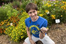 Eric Middleton posing in a flower garden with a variety of bugs crawling on him