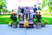Multicultural students gather around the big chair on campus